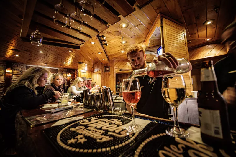 bartender pouring glasses of wine at bar