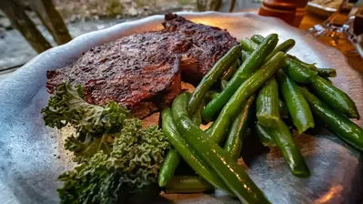 Rib eye on silver plate with green vegetables