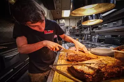 worker cuts meat at The Peddler