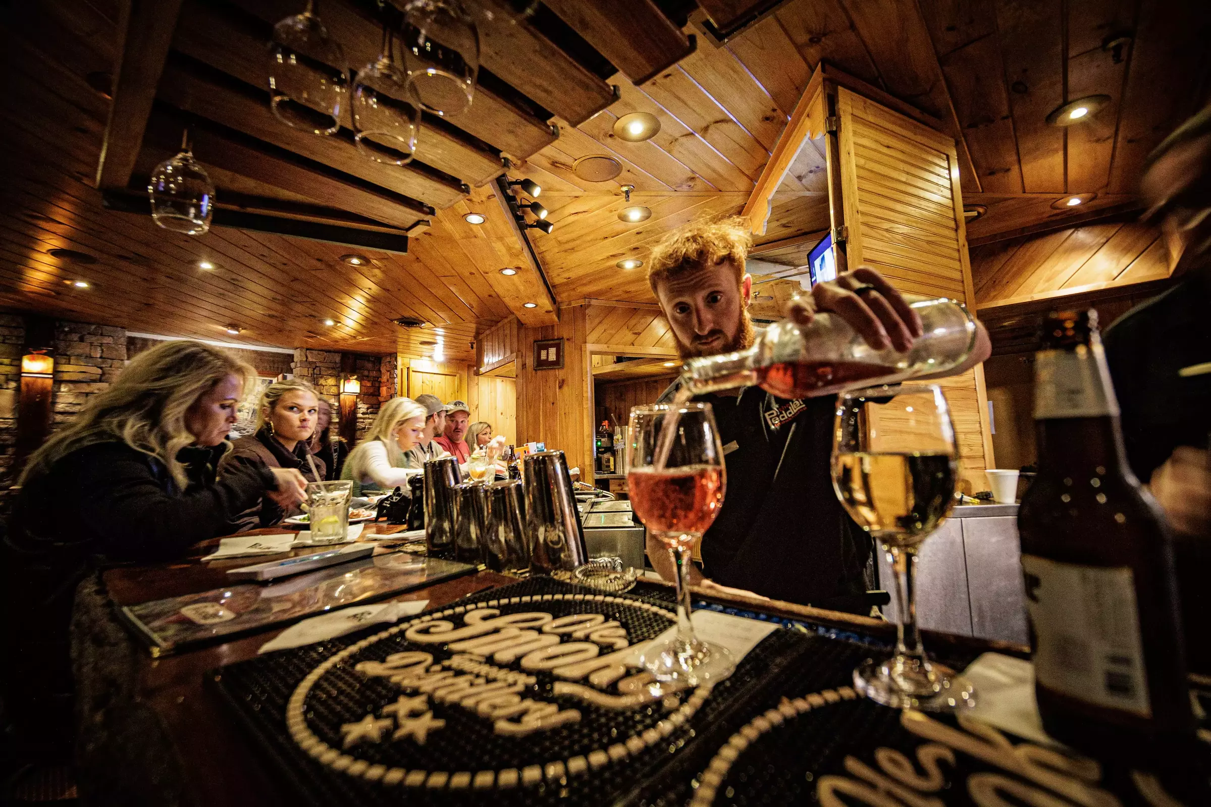 bartender pouring glasses of wine at bar