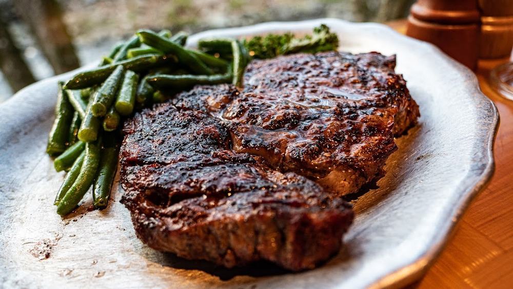 Steak on a silver plate with green vegetables